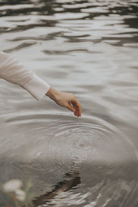 High angle view of person hand touching water in lake