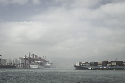 Container ship at commercial dock against cloudy sky