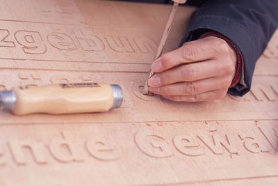 Cropped hand carving texts on wooden plank