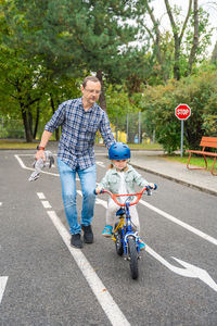 Rear view of man riding push scooter on road