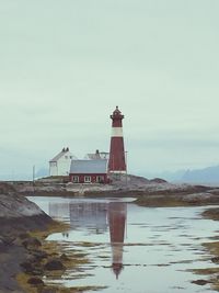 Lighthouse by sea against clear sky