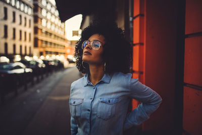 Portrait of young woman standing against building