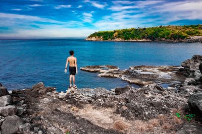 Rear view of shirtless man looking at sea against sky