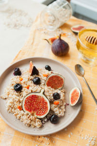  oatmeal porridge, blueberries, fresh figs and sea buckthorn , honey stick and long spoon