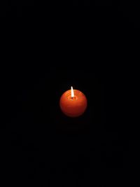 Close-up of lit candle against black background