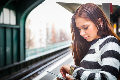 Young woman using mobile phone while sitting in train