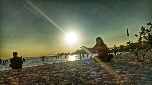 People by swimming pool at beach against sky