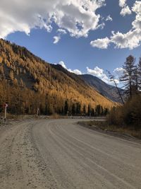 Road amidst trees and mountains against sky
