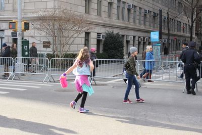 Rear view of people walking on road in city