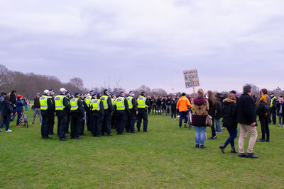 Rear view of people standing on field against sky