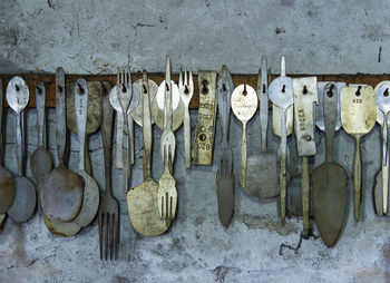 Close-up of old kitchen utensil hanging on weathered wall