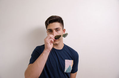 Portrait of young man standing against white background