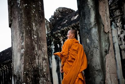 Side view of a woman against tree trunk