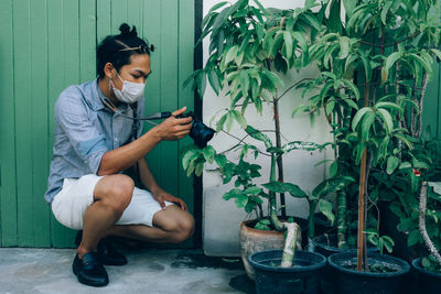 Young man using mobile phone while sitting on wall