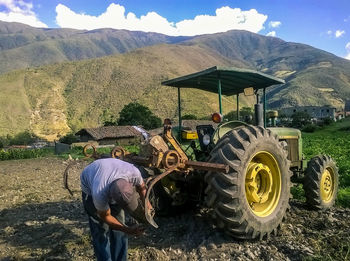 Rear view of man working on mountain against sky