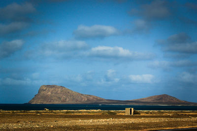 Scenic view of field by road against sky