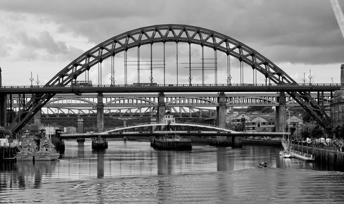 Bridge over river in city against sky