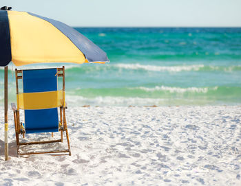 Colorful beach chair and a beach umbrella sitting on the white sandy beach in florida