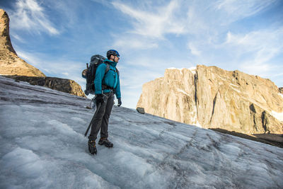 Man standing on rock against sky during winter