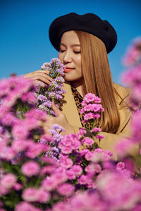 Low angle view of woman by pink flowering plants