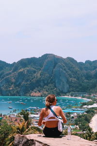 Rear view of woman looking at sea against mountain