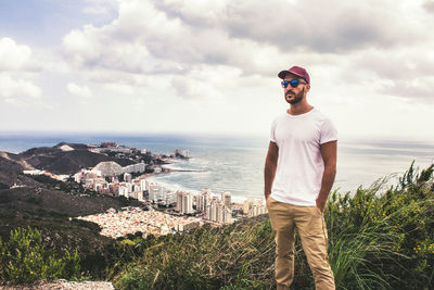 Young man standing by sea against sky