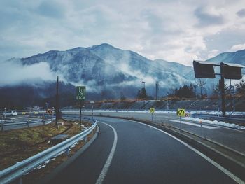 Road leading towards mountains against sky