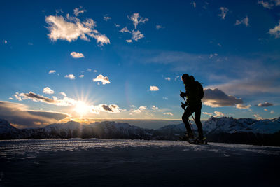 Man standing on snow against sky during sunset