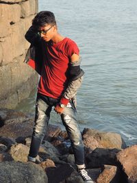 Full length of man standing on rock by sea