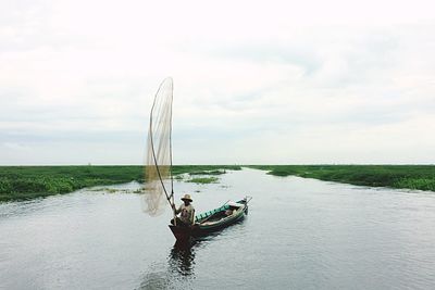 Boats in sea against cloudy sky