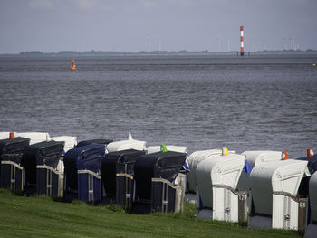 Hooded chairs on beach against sky