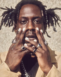 Portrait of young man holding hands up to face painted nails