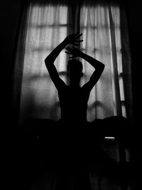 Silhouette woman with arms raised at home