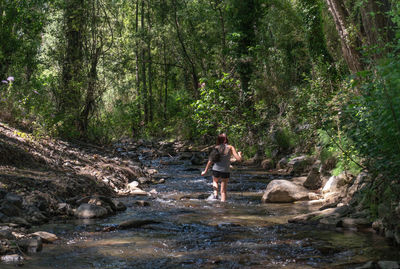 Woman walking by river in forest