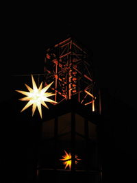 Low angle view of illuminated lamp against black background