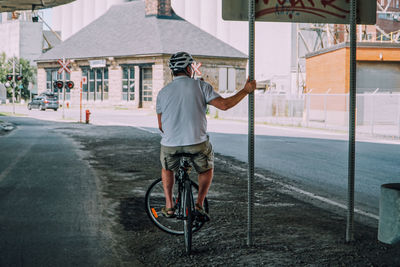 Rear view of man riding bicycle on road