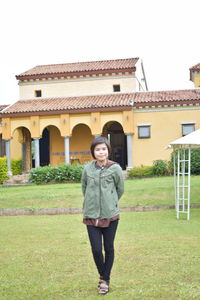 Portrait of smiling woman standing against building