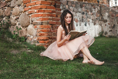 Young woman sitting on brick wall