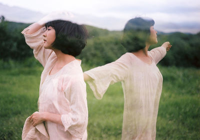 Woman with arms raised standing on field