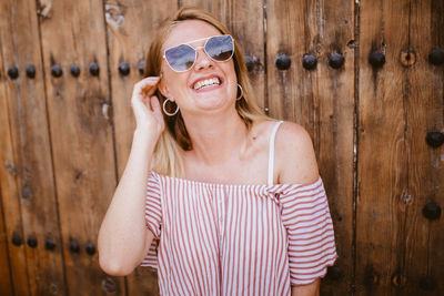 Blonde woman with sunglasses laughing and touching her hair
