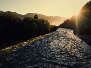 Road amidst trees against sky during sunset