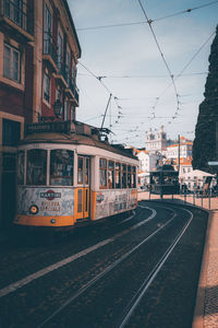 Train on railroad tracks by buildings in city against sky