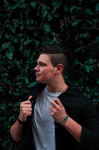 Young man looking away while standing on plant