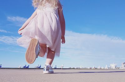 Full length of girl running on footpath against sky