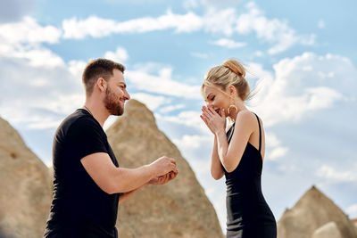 Young couple standing against sky