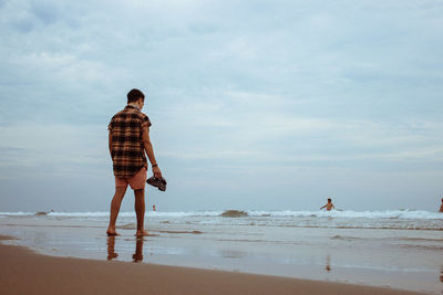 Rear view of man standing at beach