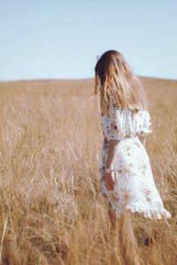 Rear view of woman on field against clear sky