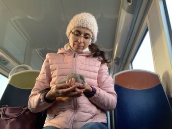 Low angle view of woman holding bird while traveling in train