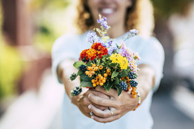 Midsection of smiling woman holding flowers
