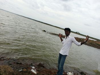 Portrait of man standing on riverbank against sky